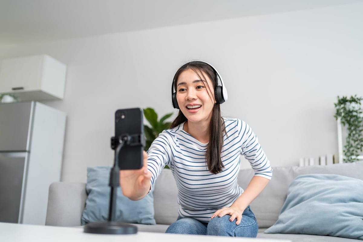 Asian woman recording dance video for TikTok in living room