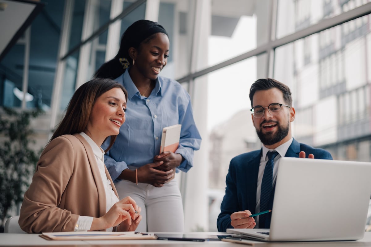 Diverse businesspeople collaborating on a project using laptop in modern office
